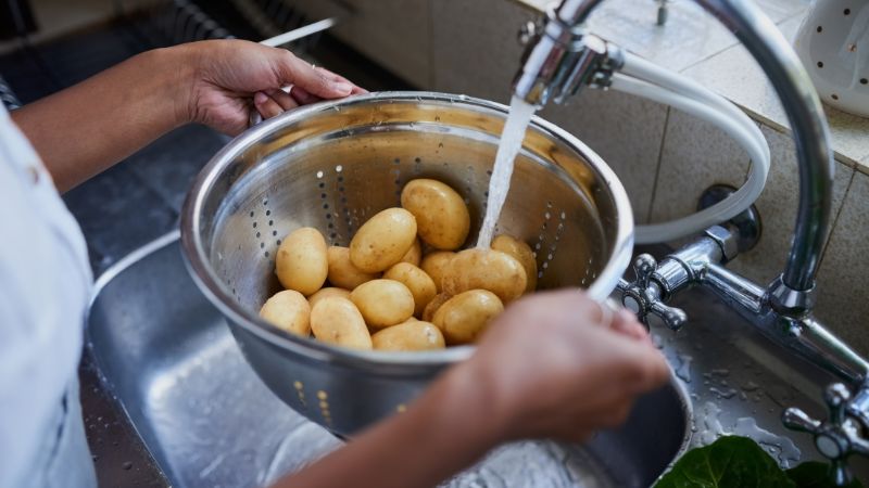 Image of person washing potatoes in the sink